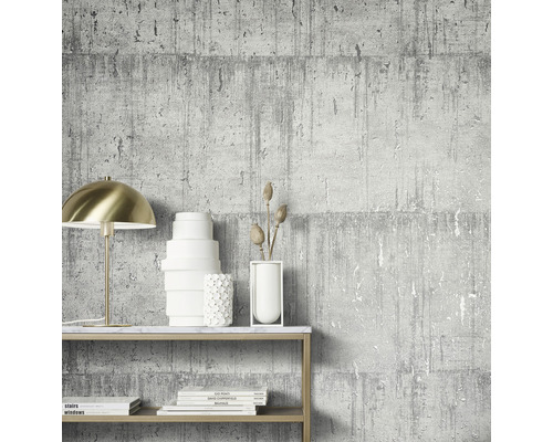 Szene mit einer grauen Tapete in Betonoptik, einer goldenen Lampe und dekorativen Gegenständen auf einem Regal