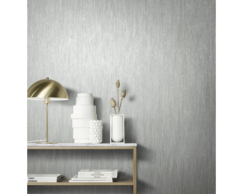 Nahaufnahme einer silberfarbenen Tapete mit vertikalem Streifenmuster in einem hellen Raum.