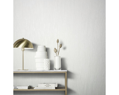 Dekoratives Stillleben mit Tischlampe, Vasen und Büchern vor einer strukturierten Tapete