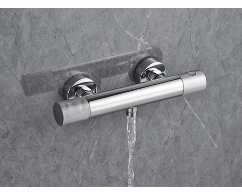 Aufputz-Thermostatbatterie mit Wasserfluss vor grauer Wand