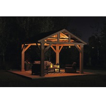 Beleuchteter Pavillon mit Gartenmöbeln auf Holzterrasse bei Nacht.