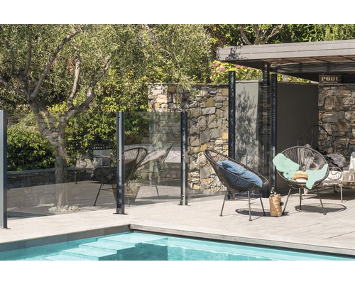 Poolbereich mit Glaszaun, Pool und Sitzgelegenheiten im Freien.