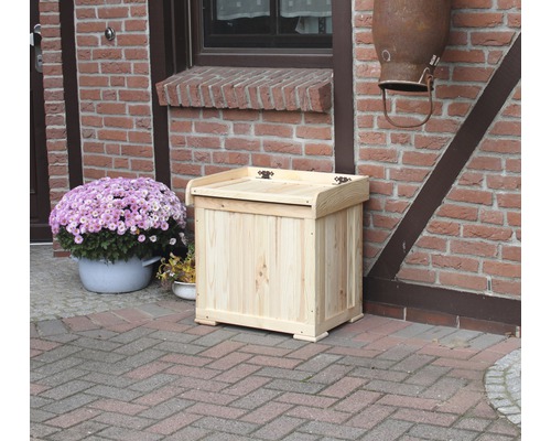 Holzkiste mit Deckel vor einem Backsteingebäude