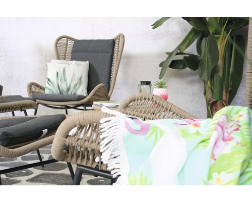 Szene mit Loungemöbeln aus Rattan und einer Zimmerpflanze im Hintergrund.