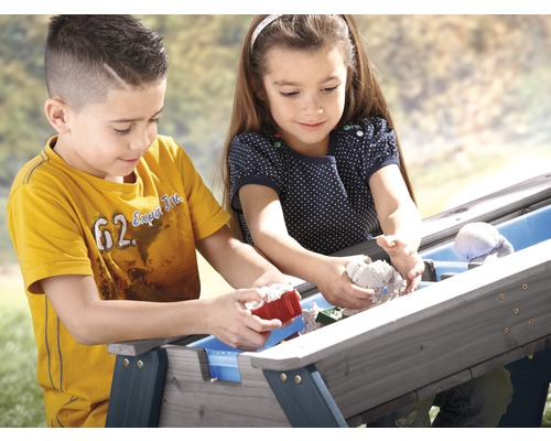Zwei Kinder spielen mit Sand an einem Sandtisch im Freien.