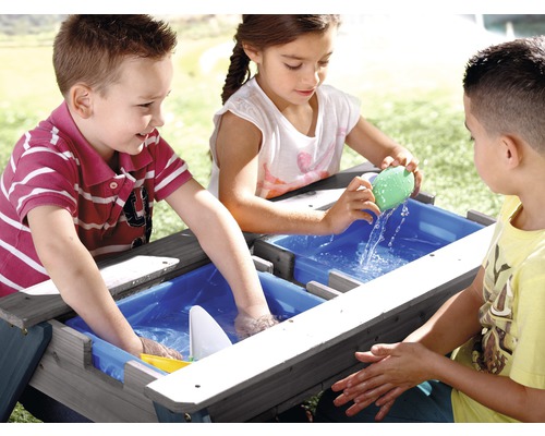 Kinder spielen mit einem Sand- und Wassertisch im Garten.