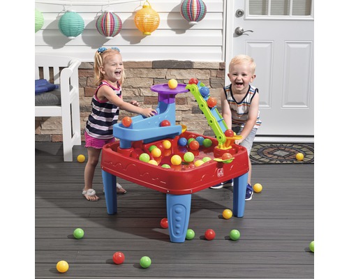 Zwei Kinder spielen mit einem Step2 Spieltisch mit bunten Bällen im Freien.