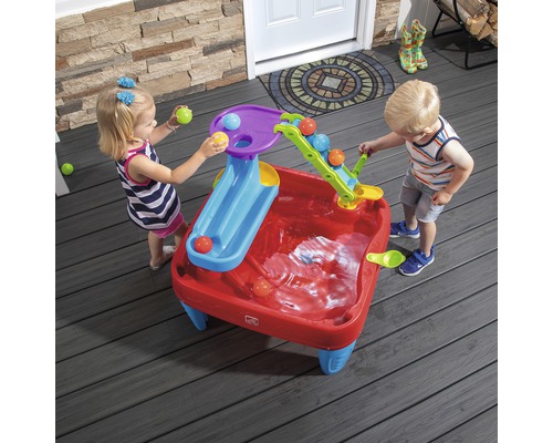 Zwei Kinder spielen mit einem Step2 Wasserspieltisch im Freien mit Rutschen und Bällen.