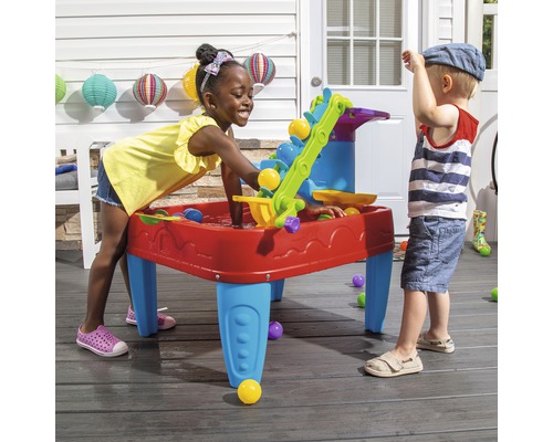 Zwei Kinder spielen mit einem Wasser- und Sandtisch im Freien.