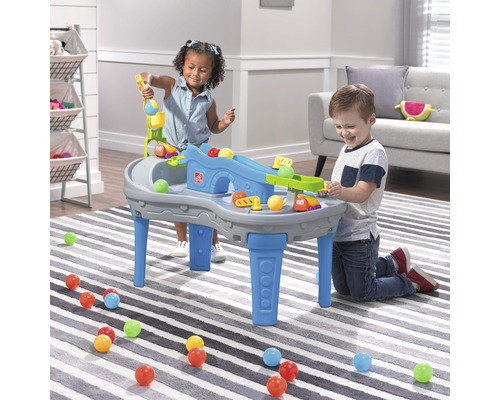 Zwei Kinder spielen mit einem Step2 Spieltisch mit Rampen und Bällen
