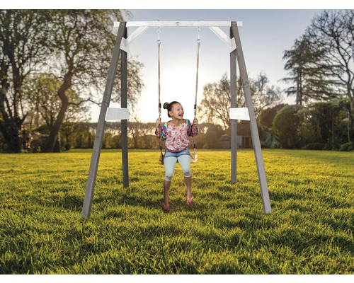 Mädchen schwingt auf einer Holzschaukel im Garten
