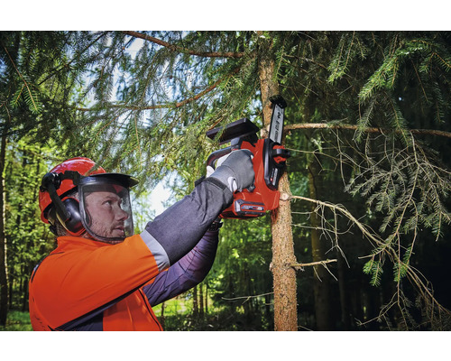 Eine Person mit Sicherheitsausrüstung benutzt eine Akku-Kettensäge, um einen Baumast zu schneiden.