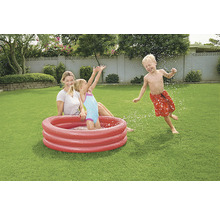 Mutter und Kinder spielen mit einem Planschbecken im Garten.