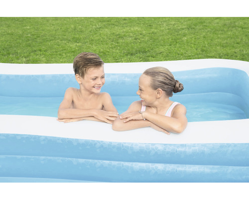 Zwei Kinder spielen in einem aufblasbaren Schwimmbecken im Garten.