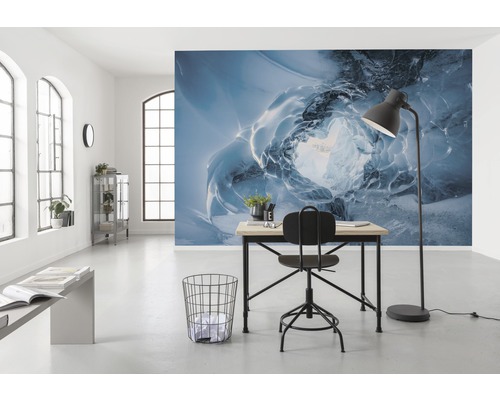 Ein helles Büro mit einem Schreibtisch, einem Stuhl und einer Fototapete mit einem Eishöhlenmotiv.