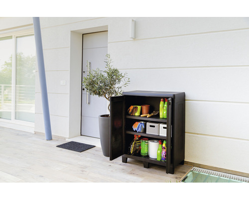 Gartenschrank mit offenstehender Tür, gefüllt mit Gartengeräten vor einem Haus