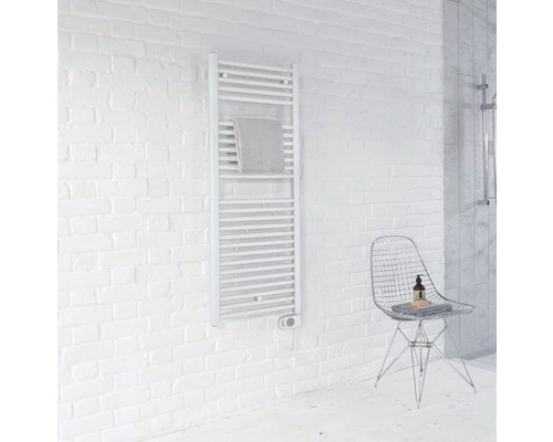 Weißer Handtuchwärmer an einer Ziegelwand in einem Badezimmer