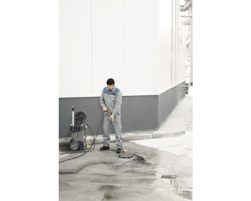 Mann reinigt Fläche mit Hochdruckreiniger und Flächenreiniger