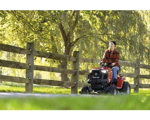 Frau fährt Rasentraktor auf Rasenfläche