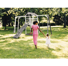Spielplatz mit Schaukel, Rutsche und Spielhaus im Garten. Eine Frau hält die Hand eines Kindes.