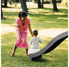 Eine Frau und ein Kleinkind an einer Rutsche im Garten.