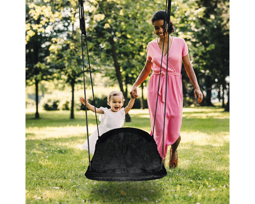 Mutter schiebt ihr Kind auf einer Nestschaukel im Garten an.