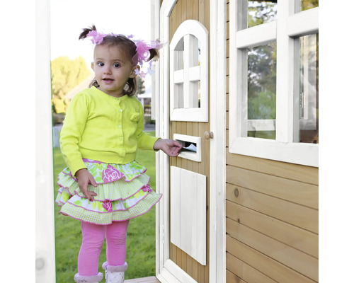 Ein kleines Mädchen steckt einen Brief in den Briefkasten eines Holzspielhauses.