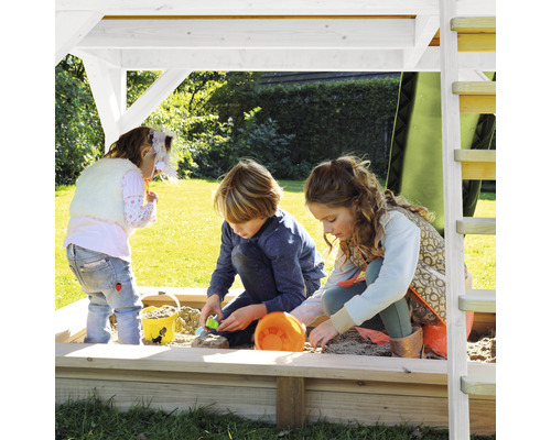 Kinder spielen im Sandkasten unter einem Spielturm auf einem Rasen
