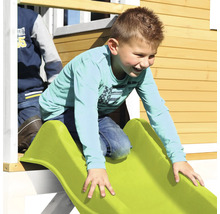 Junge rutscht auf einer grünen Rutsche an einem Spielhaus