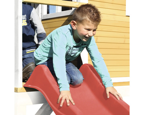 Kind rutscht auf einer roten Rutsche an einem Spielhaus