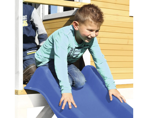 Kind rutscht auf einer blauen Rutsche eines Spielhauses.