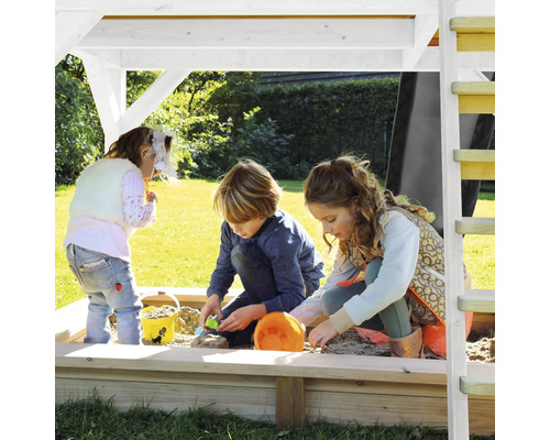 Drei Kinder spielen in einem Sandkasten mit Überdachung im Garten.