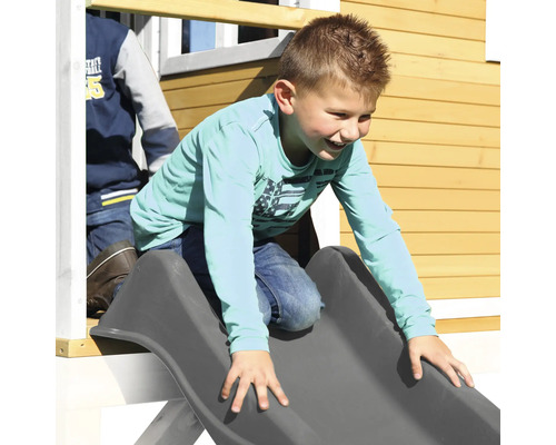 Junge rutscht auf einer Rutsche an einem Spielhaus