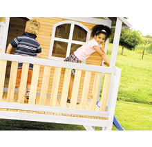 Zwei Kinder spielen in einem Holzspielhaus mit Rutsche im Garten.