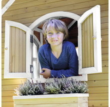 Junge schaut aus dem Fenster eines Spielhauses mit Blumenkasten