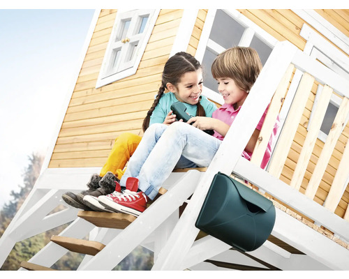 Zwei Kinder sitzen auf der Treppe eines Holzspielhauses mit Briefkasten