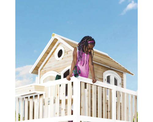 Mädchen mit Spielzeug-Fernglas auf dem Balkon eines Holz-Spielhauses im Garten