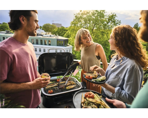Personen grillen Gemüse und Fleisch auf einem Grill im Freien.