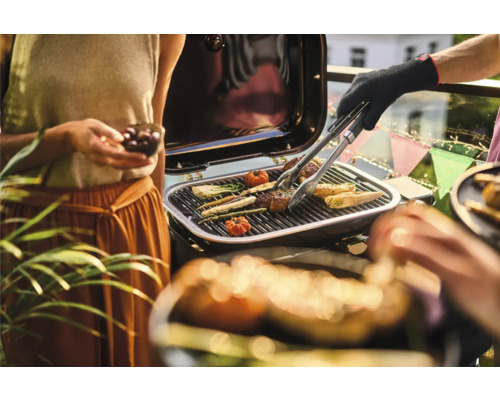 Personen grillen Gemüse und Fleisch auf einem Grill.