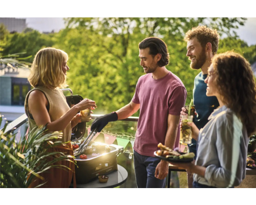 Gruppe von Menschen grillt auf dem Balkon mit einem Tischgrill