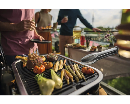 Grillszene mit Fleisch und Gemüse auf einem Grill bei einer Gartenparty.