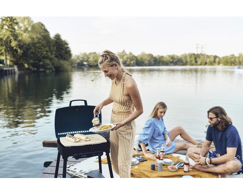 Person grillt Essen am See mit einem Explorer Gasgrill.