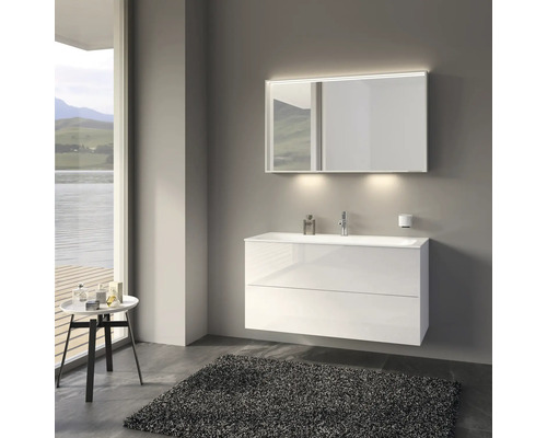 Badezimmer mit weißem Waschtischunterschrank, beleuchtetem Spiegel und Teppich