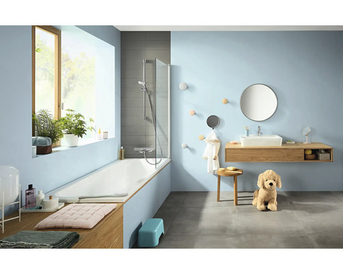 Helles Badezimmer mit Badewanne, Waschtisch und Dekorationen.