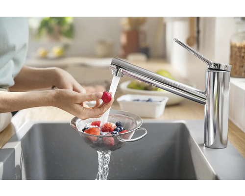 Frau wäscht Beeren unter einem Wasserhahn in der Küche
