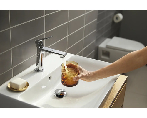 Modernes Badezimmer mit Aufsatzwaschbecken, Armatur und Person, die ein Glas Wasser befüllt