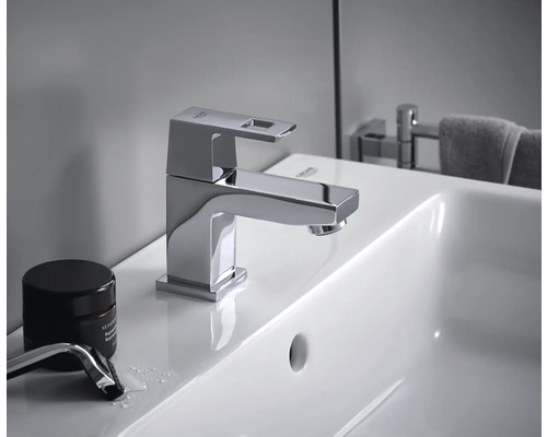 Auf einem Waschbecken ist eine glänzende Grohe Armatur mit eckigem Auslauf zu sehen.