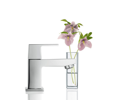 Moderner Wasserhahn aus Metall neben Blumen in Vase für das Badezimmer