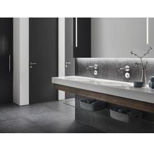 Modernes Badezimmer mit Doppelwaschbecken, Wandarmaturen, grauen Fliesen und Türen.