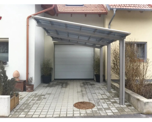 Carport aus Metall vor einer Garage und einem Wohnhaus